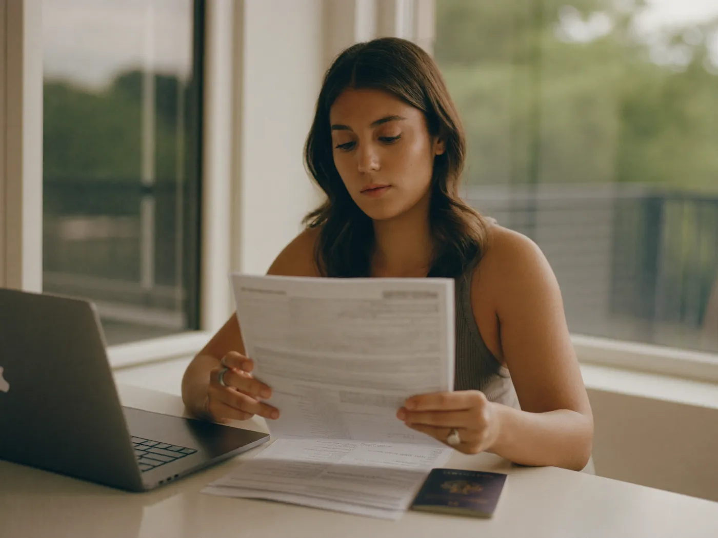 Una mujer revisa sus documentos de impuestos junto a su pasaporte y una laptop